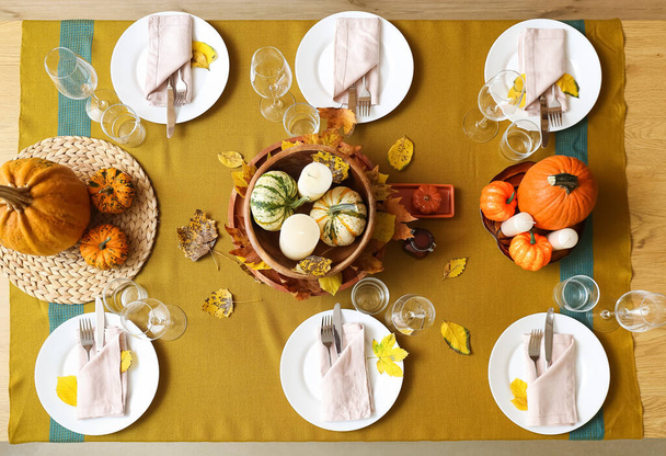 Beautiful table setting with fresh pumpkins and fallen leaves in room - Valokuva, kuva