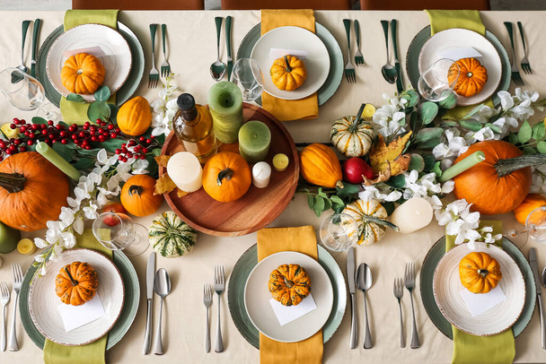 Herbstliche Tischdekoration mit frischen Kürbissen und Blumen im Zimmer - Foto, Bild