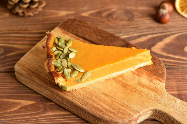 Board with piece of delicious pumpkin pie on wooden background - Foto, Imagem