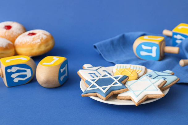 Lekkere koekjes voor Chanoeka viering en dreidels op kleur achtergrond - Foto, afbeelding