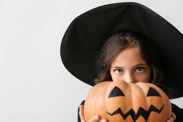 Cute little girl dressed as witch for Halloween on light background - Foto, afbeelding