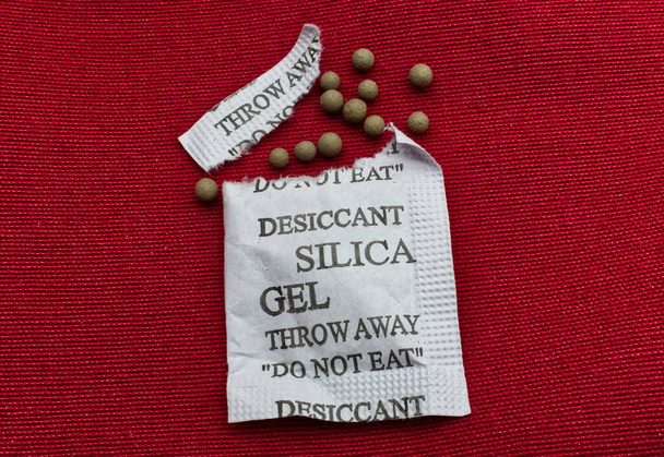 Desiccant silica gel on red background. Synthetic substance absorbing moisture - Photo, Image
