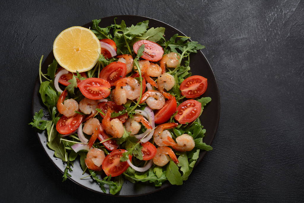 Fresh salad plate with shrimps, onions, lemon, tomatoes and mixed greens (arugula, mesclun, ) - Foto, afbeelding