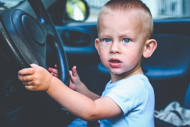 One year old baby boy sit behind the wheel and pretend driving car - Photo, Image