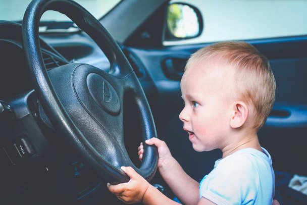 One year old baby boy sit behind the wheel and pretend driving car - Foto, imagen