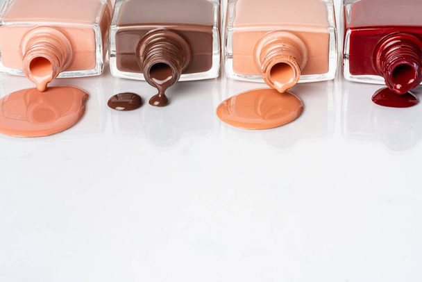 Nude colors nail polish spilled over white background - Foto, Bild