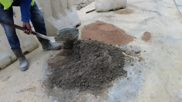 местный строитель смешивает цемент и желтый песок в куче с лопатой замедленного движения близкого зрения. - Кадры, видео