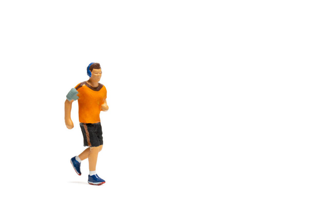 Personas en miniatura, Hombre en ropa deportiva corriendo sobre fondo blanco y espacio para el texto - Foto, Imagen