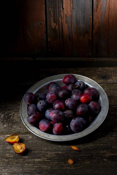 Plum in the iron bowl on a wooden background - Fotografie, Obrázek