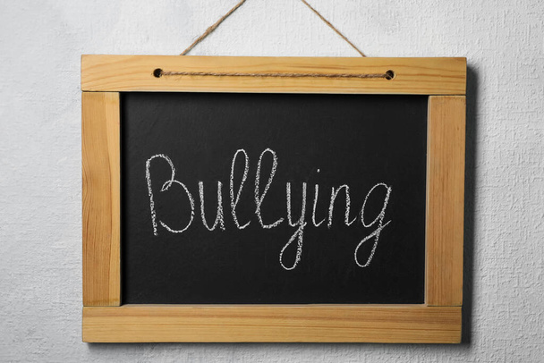Blackboard with phrase Bullying on grey wall - 写真・画像