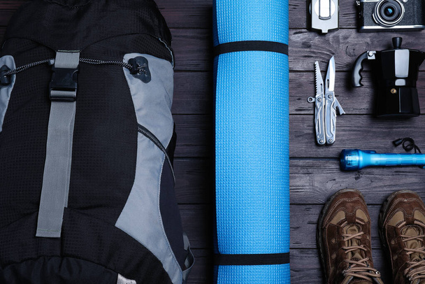 Flat lay composition with backpack and other different camping equipment for tourism on wooden background - Photo, image