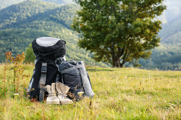 Backpack, sleeping bag and boots on lawn, space for text. Tourism equipment - Fotoğraf, Görsel