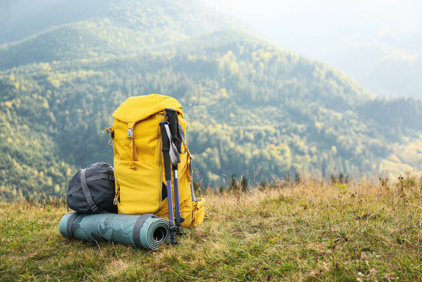 Backpack, trekking poles and sleeping mat in mountains, space for text. Tourism equipment - Fotoğraf, Görsel