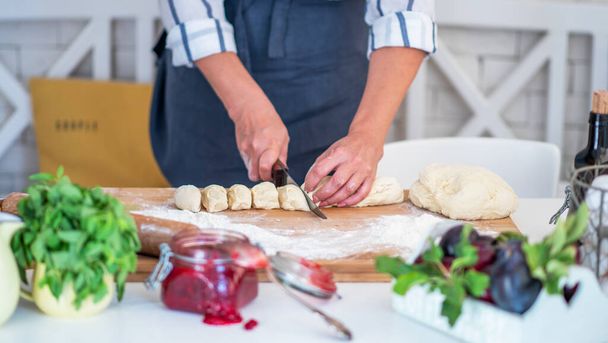 Cook hands kneading dough, piece of dough with white wheat flour. Cooks roll the dough for baking, pieces of raw dough on the wooden board. - 写真・画像