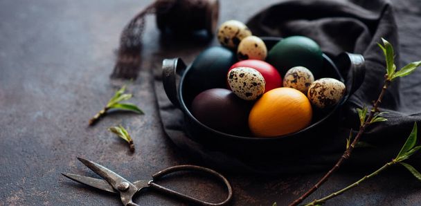 Vintage iron tray full of colorful Easter eggs with hay and spring branch on a dark rustic background. Copy space. - Foto, Imagem