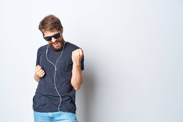 przystojny mężczyzna w okularach słuchający muzyki na słuchawkach na odosobnionym tle. Wysokiej jakości zdjęcie - Zdjęcie, obraz