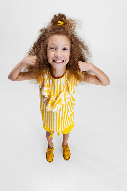 High angle view of little cute curly preschool beautiful girl looking at camera isolated over white studio background. - Φωτογραφία, εικόνα
