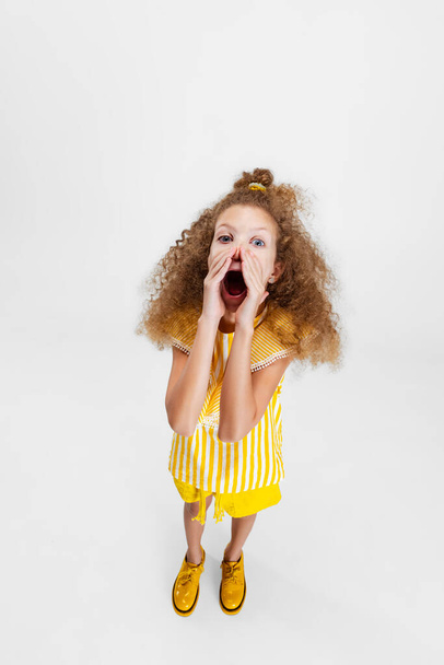 High angle view of little cute curly preschool beautiful girl shouts out loud isolated over white studio background. - Fotó, kép