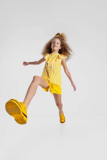 Portrait of little active Caucasian preschool girl posing at camera isolated over white background. In motion - Φωτογραφία, εικόνα