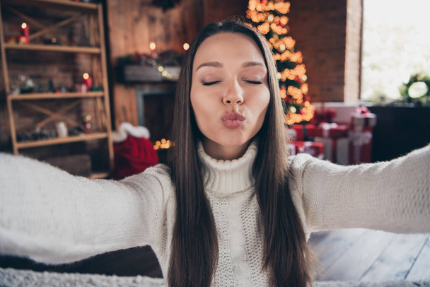 Photo of adorable cute young woman dressed knitted sweater tacking selfie sending you kiss indoors room home house - Foto, imagen