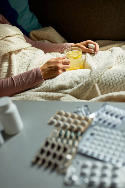 Nemocná žena drží hrnek teplého čaje z rakytníku a sedí pod dekou doma, nemocná paní. - Fotografie, Obrázek