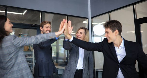 Happy people standing in office and giving high five to their colleagues - Фото, изображение