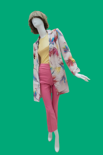 Volledige afbeelding van een vrouwelijke etalagepop dragen zomer modieuze kleding geïsoleerd op een groene achtergrond - Foto, afbeelding