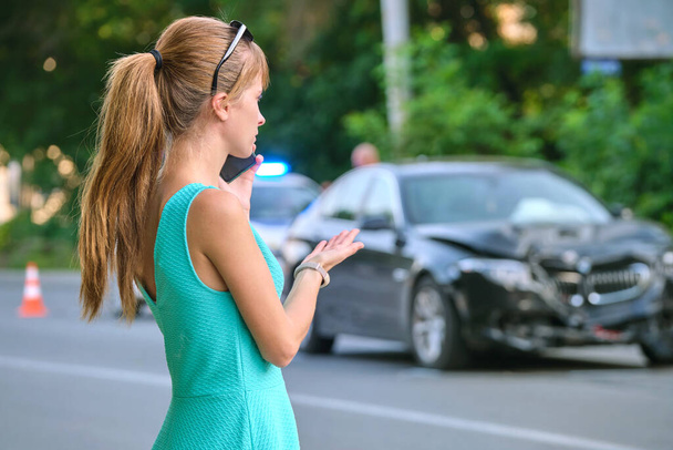 Smutna kobieta mówi przez telefon na ulicy, wzywając pogotowie po wypadku samochodowym. Koncepcja bezpieczeństwa ruchu drogowego i ubezpieczenia. - Zdjęcie, obraz