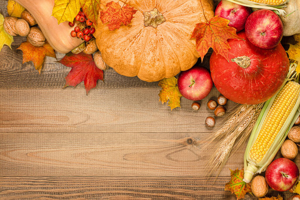 カボチャ、リンゴ、トウモロコシ、ナッツ、ベリー、木のテーブルの上の葉、感謝祭の日の秋の組成、トップビュー - 写真・画像