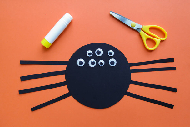 Das Kind bastelt eine schwarze Spinnendekoration. Halloween-Party. Kunstprojekt für Kinder. DIY-Konzept. Schritt-für-Schritt-Anleitung. Schritt 5 - Foto, Bild