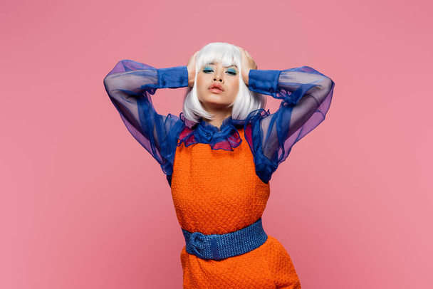 Young asian model in retro clothes and white wig looking at camera isolated on pink  - Zdjęcie, obraz