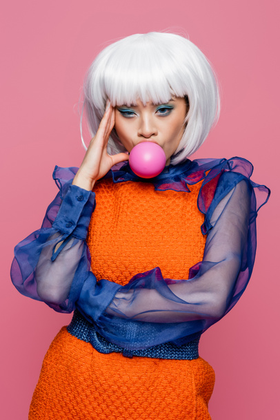 Pretty asian woman in white wig blowing bubble gum isolated on pink  - Photo, Image