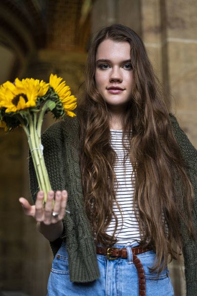 Young brunette woman holding bouquet of fresh sunflowers in her hand - Foto, afbeelding