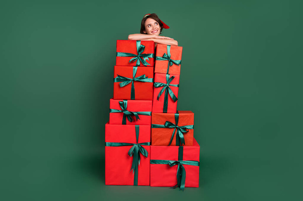 Photo of dreamy creative lady pile box look empty space enjoy rest wear elf costume hat isolated green color background - Foto, Imagen