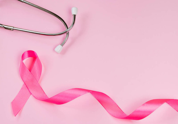Pink ribbon and stethoscope on colored background. Breast Cancer Awareness Month. Women's health care concept. Symbol of fight against oncology. Copy space. - Photo, Image