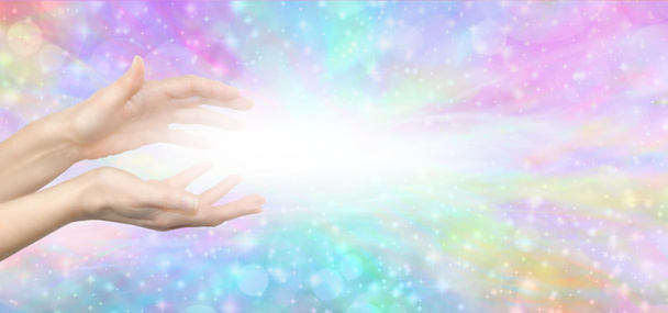 Reiki Lightworker Healing Hands and white light message banner - female hands with white light between against a multicoloured ethereal shimmering background with copy space - Photo, Image