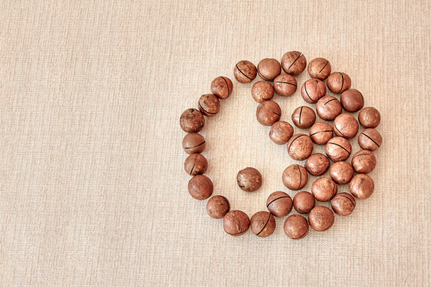The male and female Yin-Yang symbol is made of macadamia nuts on a light brown background - Fotoğraf, Görsel