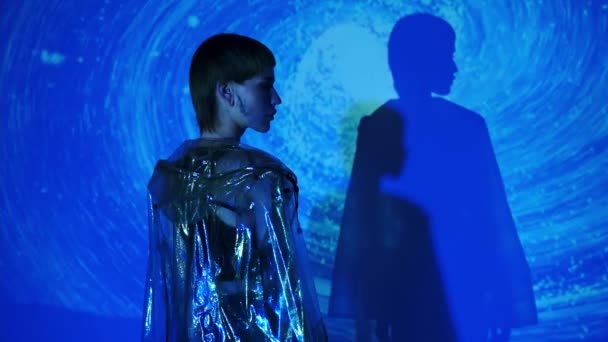 Медленное движение стильной женщины, поворачивающейся к камере на абстрактном синем фоне  - Кадры, видео