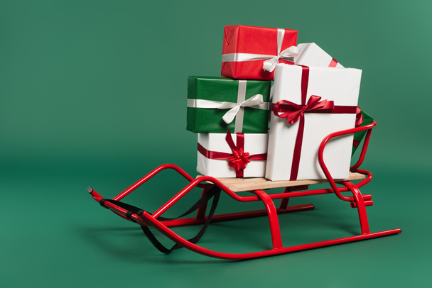 Cadeaux avec des arcs sur traîneau sur fond vert  - Photo, image
