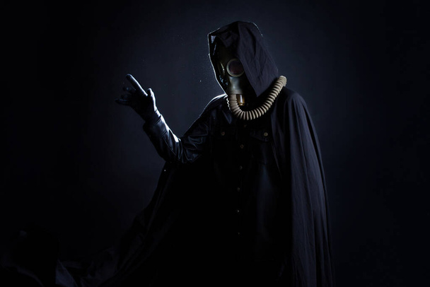 Post-apokalyptischer Charakter, eine gruselige Geschichte, eine Konzeptfigur mit Gasmaske und schwarzem Mantel - Foto, Bild