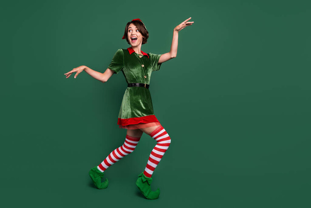 Volledige lengte lichaam grootte uitzicht van aantrekkelijke vrolijke grappige meisje dansen plezier geïsoleerd over groene kleur achtergrond - Foto, afbeelding