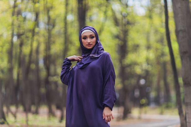 Islamic beautiful woman in a Muslim dress standing on a summer park street background forest autumn trees.world hijab day. - Fotoğraf, Görsel