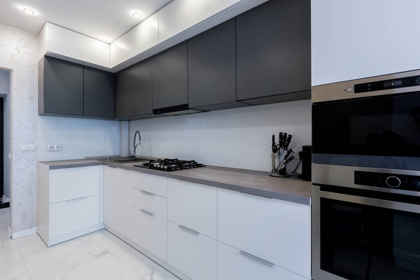 keuken interieur met grijze inzetstukken en donkere elementen in een moderne stijl - Foto, afbeelding