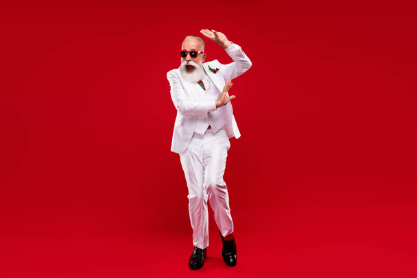 Full body photo of funny happy old man dance good mood wear three piece suit xmas isolated on red color background - Foto, immagini