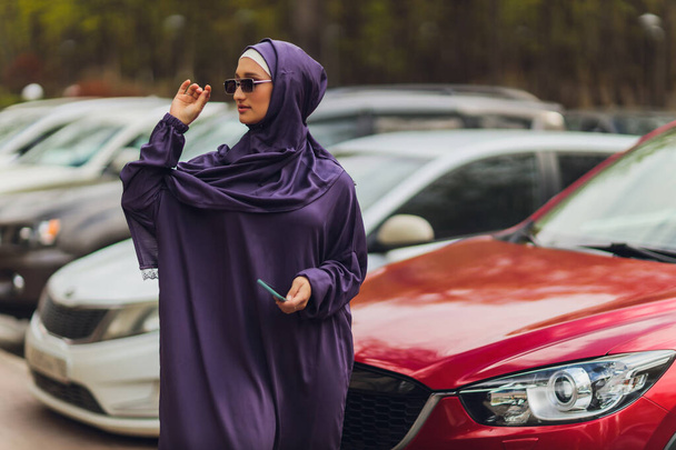 Islamic beautiful woman in a Muslim dress standing on a summer park street background forest autumn trees.world hijab day. - Photo, Image