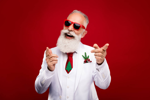 Photo of cool aged grey hair man point camera wear eyewear white jacket isolated on red color background - Foto, Imagen