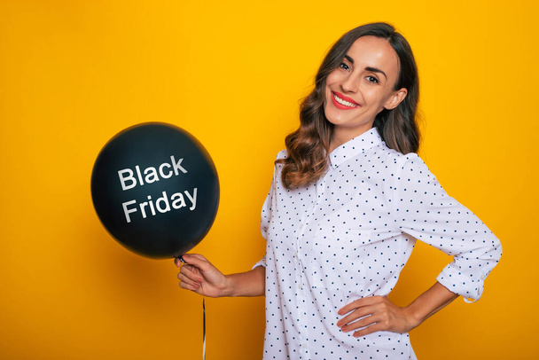 Close up photo of beautiful excited happy woman with a black helium balloon in hand like a symbol of black Friday and shopping day - Foto, immagini