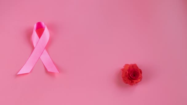 Месяц осведомленности о раке груди. Розовая лента и цветок на цветном фоне. Прекратить показ видео для рекламы и продвижения кампании по борьбе с раком. Концепция поддержки и помощи. - Кадры, видео