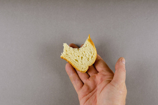 Ruka drží pokousanou půlku plátku pšeničného chleba. Dospělá ma - Fotografie, Obrázek