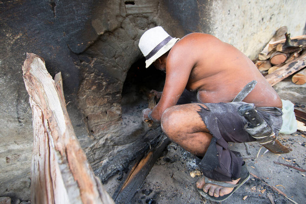 man putting logs in fireplace, rear view, travel shot - Foto, Bild